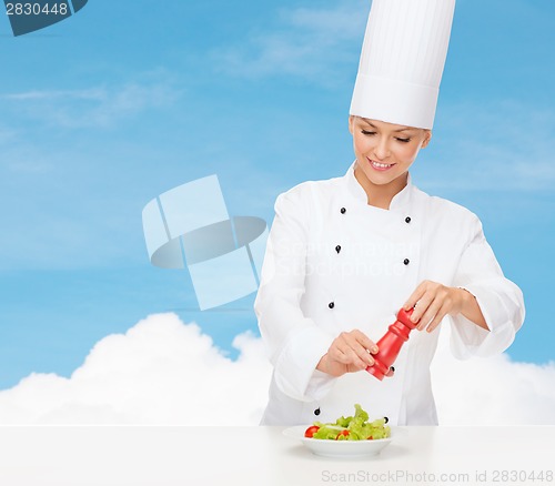 Image of smiling female chef with preparing salad