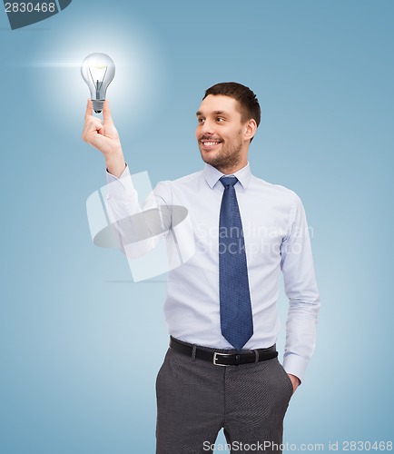 Image of handsome businessman holding light bulb