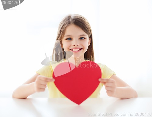 Image of smiling little girl with red heart at home