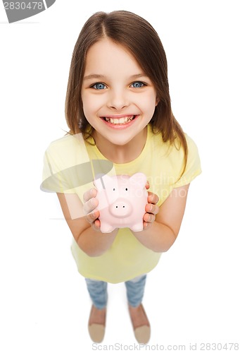 Image of beautiful little girl with piggy bank