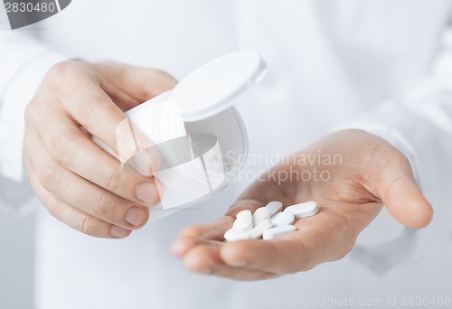 Image of doctor hands holding white pack and pills