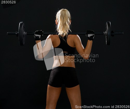 Image of sporty woman exercising with barbell from back