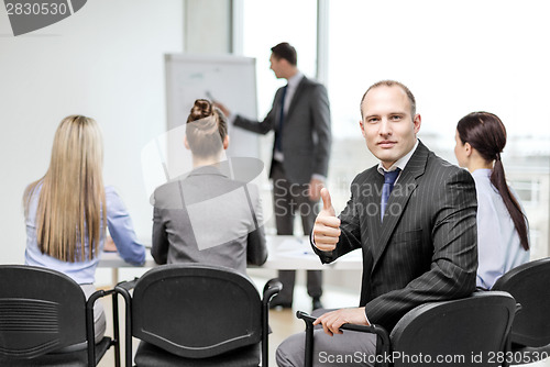 Image of businessman with team showing thumbs up in office