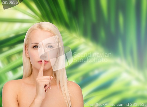 Image of calm young woman with finger on lips