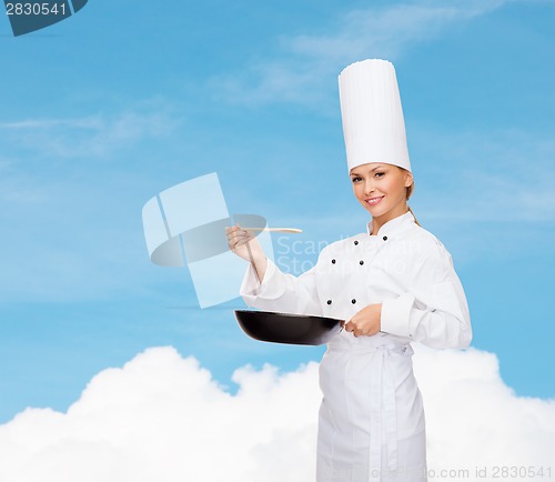 Image of smiling female chef with pan and spoon