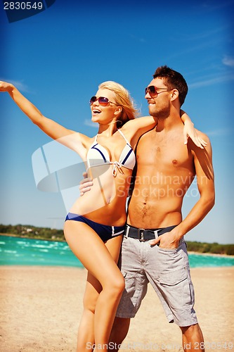 Image of happy couple in sunglasses on the beach