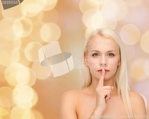 Image of calm young woman with finger on lips