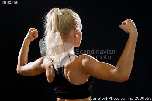 Image of sporty woman from the back flexing her biceps