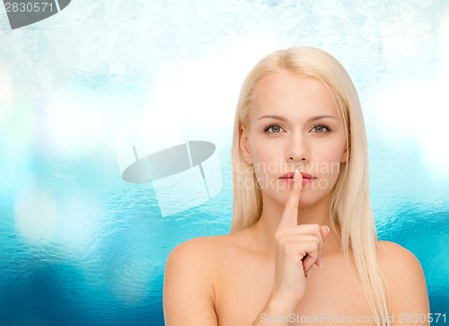 Image of calm young woman with finger on lips