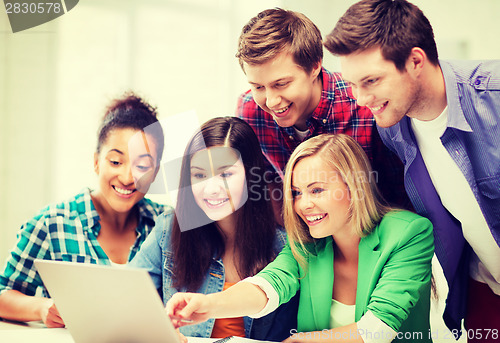 Image of smiling students looking at laptop at school