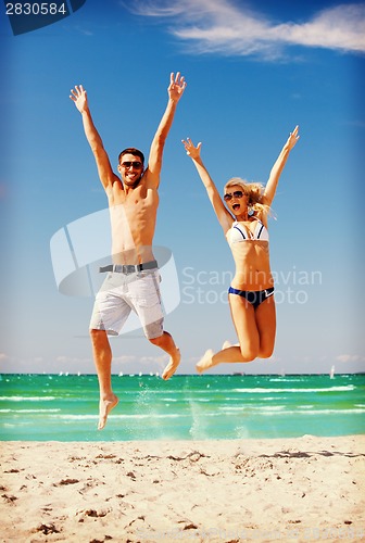 Image of happy couple jumping on the beach