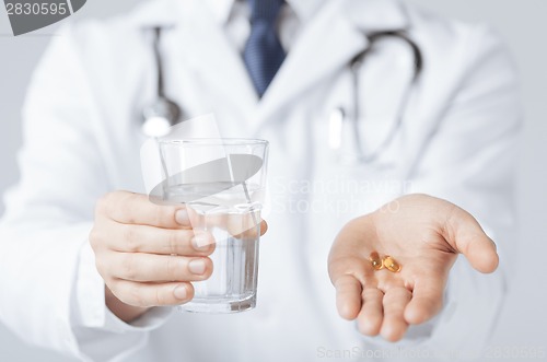 Image of doctor hands giving capsule and glass of water