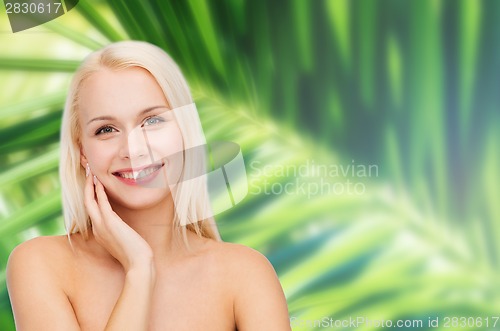 Image of smiling young woman touching her face skin