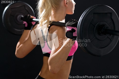 Image of sporty woman exercising with barbell from back