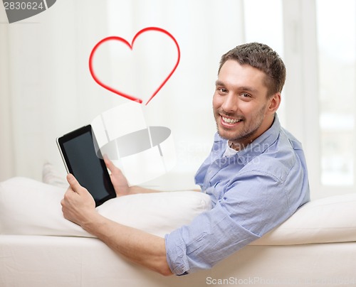 Image of smiling man working with tablet pc at home