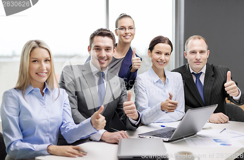 Image of business team showing thumbs up in office