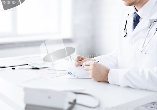 Image of male doctor writing prescription paper