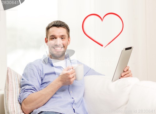 Image of smiling man working with tablet pc at home