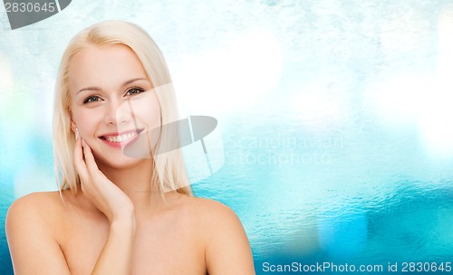 Image of smiling young woman touching her face skin