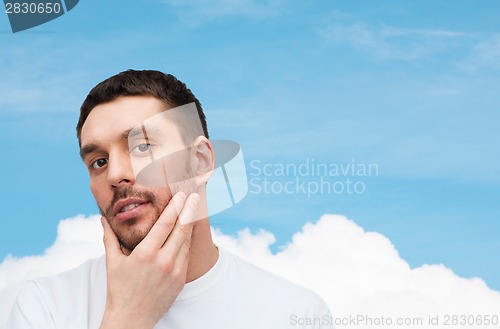 Image of beautiful calm man touching his face