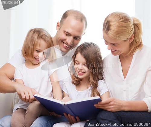 Image of smiling family and two little girls with book