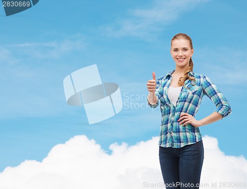 Image of young woman in casual clothes showing thumbs up