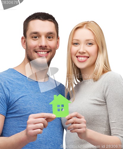 Image of smiling couple holding green paper house