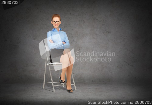 Image of smiling businesswoman in glasses sitting on chair