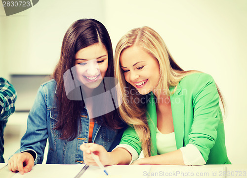 Image of student girls pointing at notebook at school