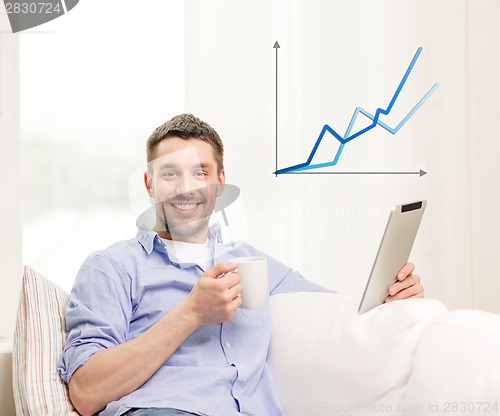 Image of smiling man working with tablet pc at home