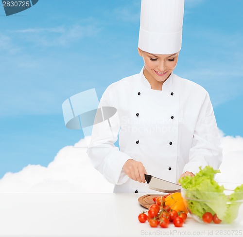 Image of smiling female chef chopping vegetables