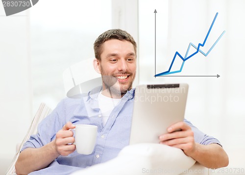 Image of smiling man working with tablet pc at home