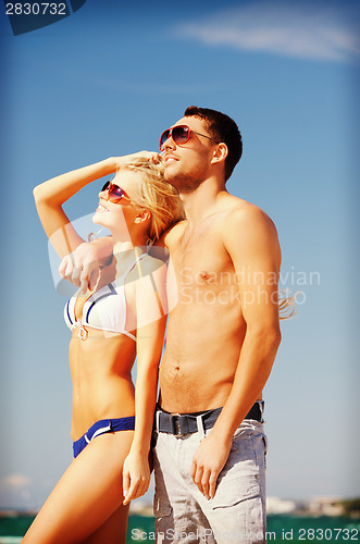 Image of happy couple in sunglasses on the beach