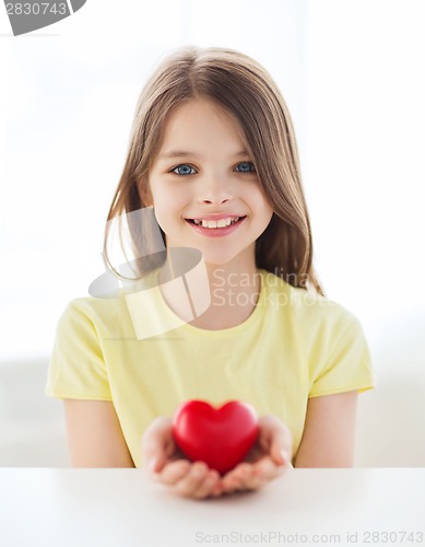 Image of smiling little girl with red heart at home