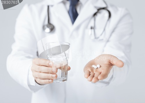 Image of doctor hands giving white pills and glass of water