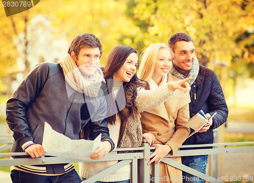 Image of couples with tourist map in autumn park