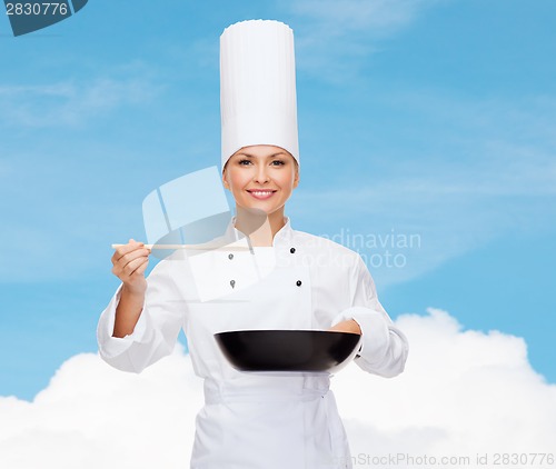 Image of smiling female chef with pan and spoon