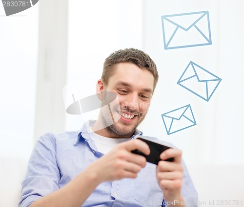 Image of smiling man with smartphone at home