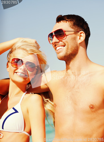 Image of happy couple in sunglasses on the beach