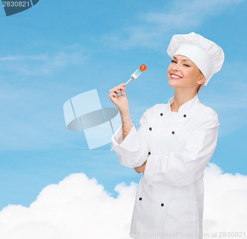 Image of smiling female chef with fork and tomato