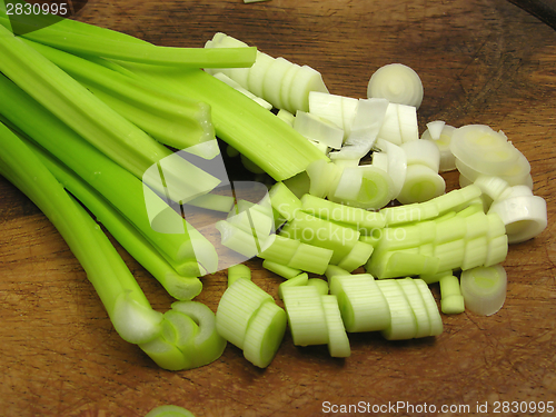 Image of Sliced spring onions on brown wooden plate