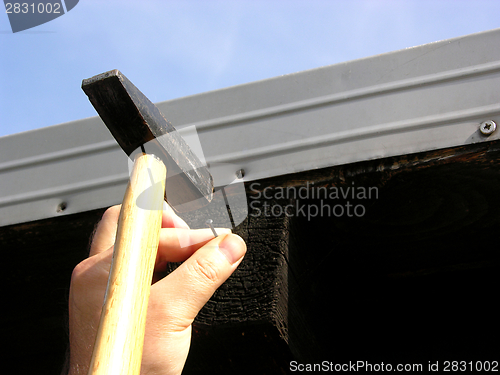 Image of Man bangs a nail into a wooden wall