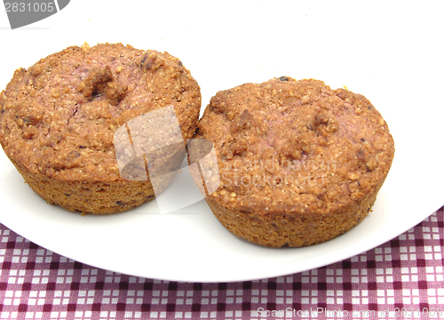 Image of Two raspberry muffins on a white plate of chinaware