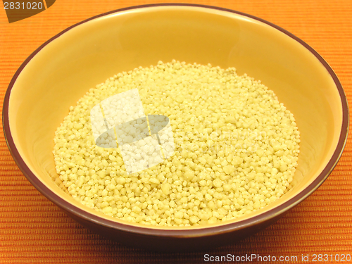 Image of Yellow couscous in a orange bowl of ceramic on an orange background