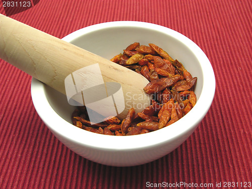 Image of Pestling dried red hot chili pepper in a bowl of chinaware