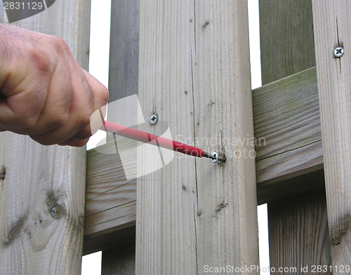 Image of Cutout hand with screw driver on wooden fence