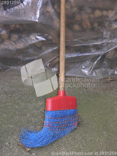 Image of Old and nagged blue plastik broom with wooden stick