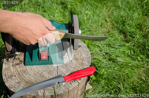 Image of Hand grinder knife with electric tool outdoor log 