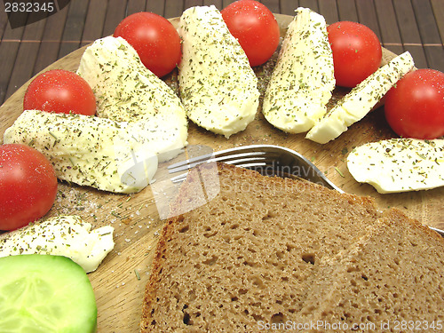 Image of Sliced mozzarella with little tomatoes, a slice of cucumber and