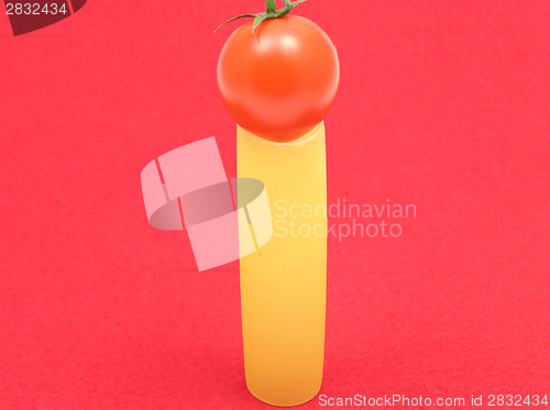 Image of One unboiled canneloni with one tomato on red felt